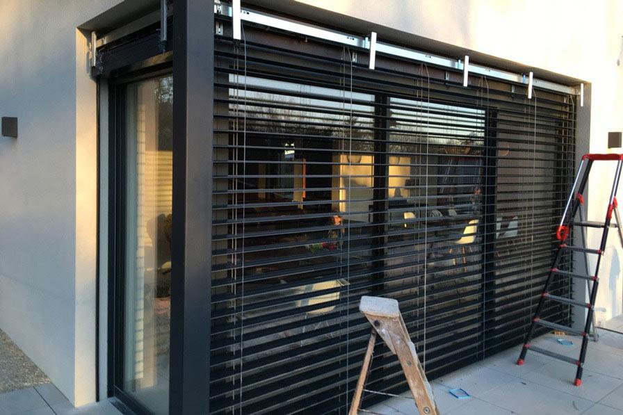 Store vertical protégeant une baie vitrée du soleil